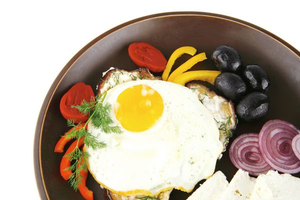 تخم مرغ سرخ شده در ظرف تیره با سبزیجات سرو می شود