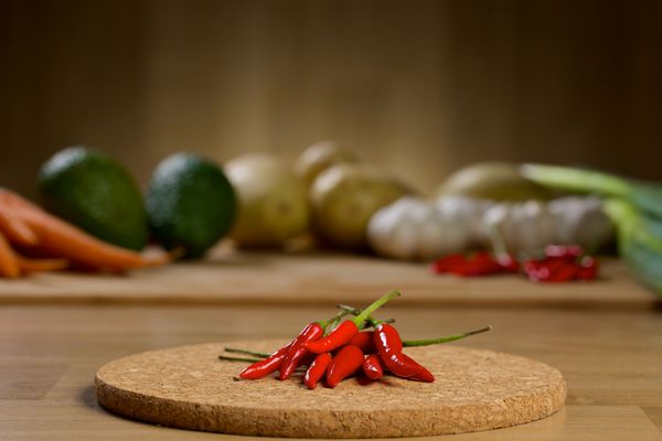 فلفل قرمز قرمز روی میز چوبی با سبزیجات در پس زمینه