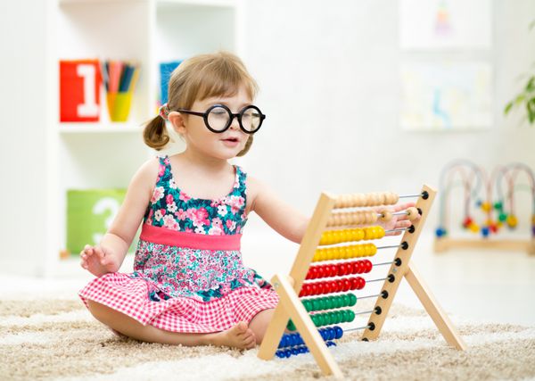 کودک کودک عینکی با اسباب بازی چرتکه در داخل خانه می زد