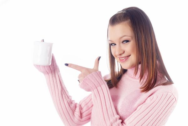 زن جوان جذاب با انگشت به فنجان قهوه اشاره می کند