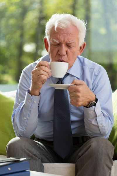 پیرمردی زیبا در حال نوشیدن قهوه در دفترش