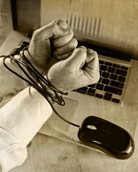 دستان تاجر قفقازی معتاد به کار بسته و با موس کامپیوتری با دستبند با لپ تاپ در مفهوم سیاه و سفید معتاد به کار برده اینترنتی و معتاد