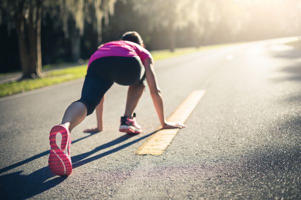 زن ورزشکار که در فضای باز کار می کند خانم جوان در حال انجام تمرینات و آماده برای شروع دویدن مفهوم سلامت و ورزش