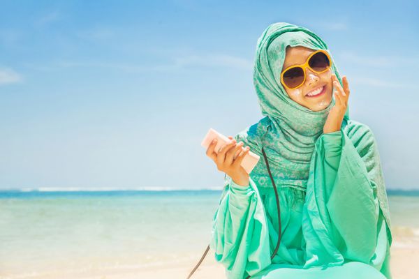 مفهوم کامل محافظت در برابر آفتاب دختر زیبا در ساحل با لباس سنتی مسلمان
