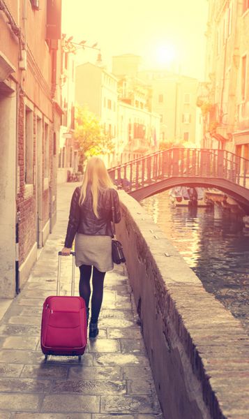 زنی که صبح با چمدان در پیاده‌روی ونیز راه می‌رود