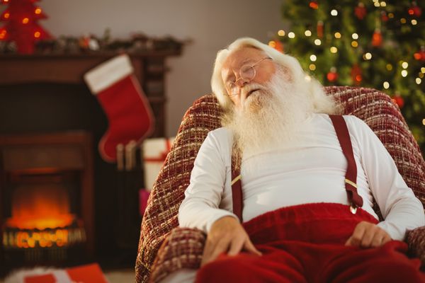 چرت زدن بابا نوئل روی صندلی راحتی در خانه در اتاق نشیمن