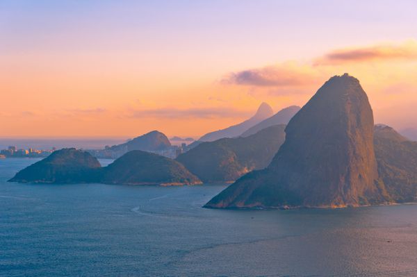 کوه قندیل از پشت در هنگام غروب سرخ با منظره تپه ها و اقیانوس ریودوژانیرو برزیل