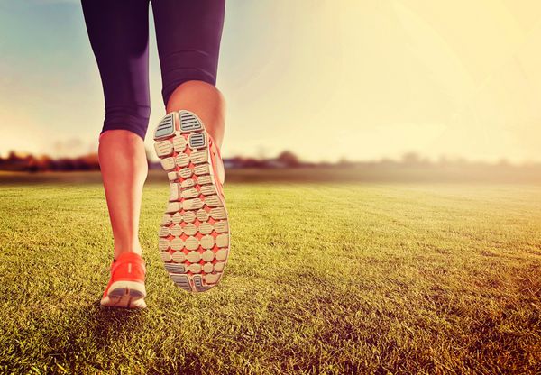 یک جفت پا ورزشی روی چمن هنگام طلوع یا غروب خورشید - مفهوم سبک زندگی سالم