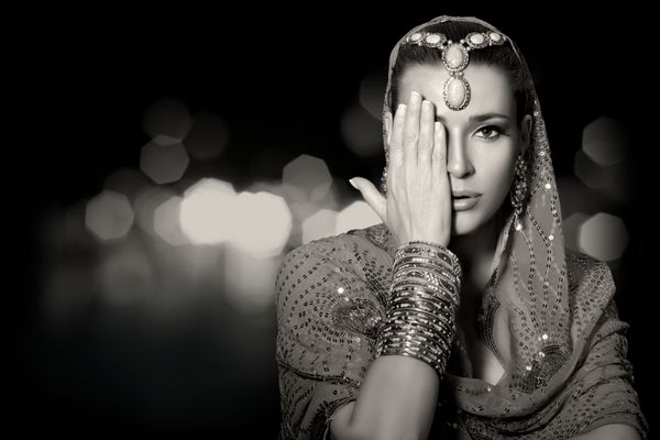 مد زیبایی قومی زن زیبای هندی با لباس های سنتی جواهرات و آرایشی که نیمی از ف را با یک دست می پوشاند پرتره تک رنگ جدا شده روی مشکی با کپی sp