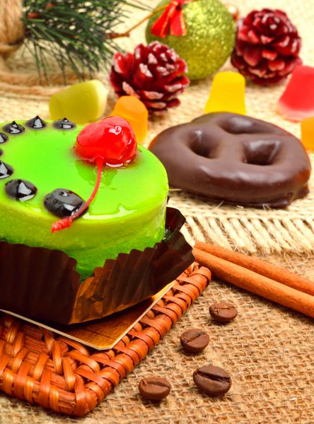 کیک سبز خوشمزه کریسمس با چوب گیلاس و دارچین در پس زمینه کریسمس