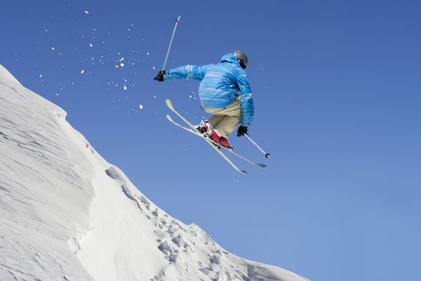 اسکی باز پرش آزاد از طریق هوا در پس زمینه آسمان آبی