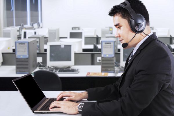 تاجر جوانی که با رایانه لپ‌تاپ و هدفون در دفتر کار می‌کند که نماد پشتیبانی مشتری است
