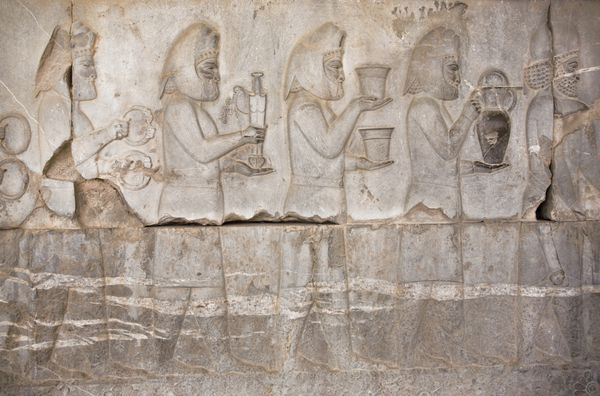 نقش برجسته سنگی با افراد باستانی که غذا و سلاح های لبه دار در دست دارند در تخت جمشید استان فارس ایران