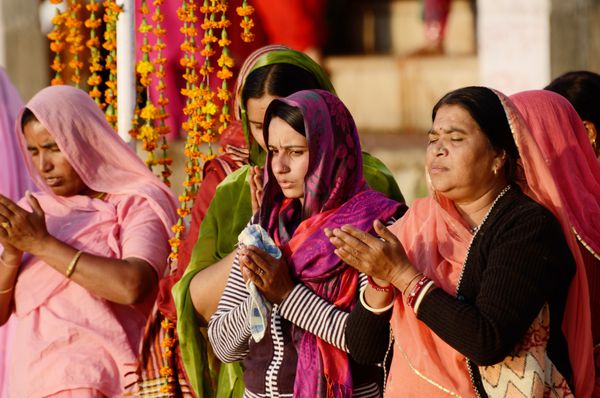 پوشکار هند - 12 نوامبر زنان مسن و جوان ناشناس با ساری روشن در هنگام غروب آفتاب در دریاچه سارووار در 12 نوامبر 2013 در پوشکار هند پوجا را اجرا می کنند این عبادت معروف در هند است