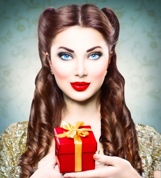 دختر زیبایی با جعبه هدیه تعطیلات در دستش پرتره زن رترو آرایش و مدل موی مدل قدیمی خانم سبک
