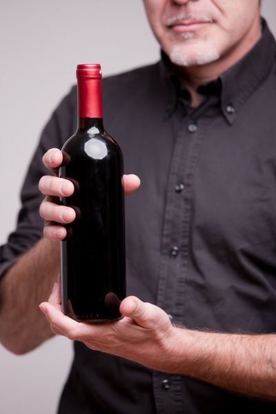 یک کارشناس ارشد در حال نشان دادن یک بطری قرمز