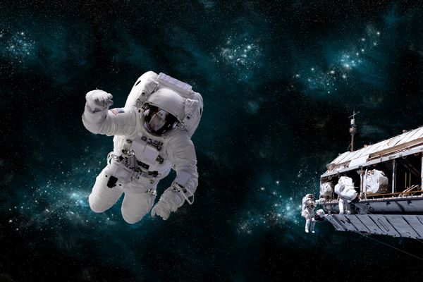 تصویری از یک فضانورد شناور در فضای بیرونی در حالی که فضانوردان همکار او در ایستگاه sp کار می کنند یک صحنه کهکشانی به عنوان پس زمینه عمل می کند عناصر این تصویر ارائه شده توسط ناسا