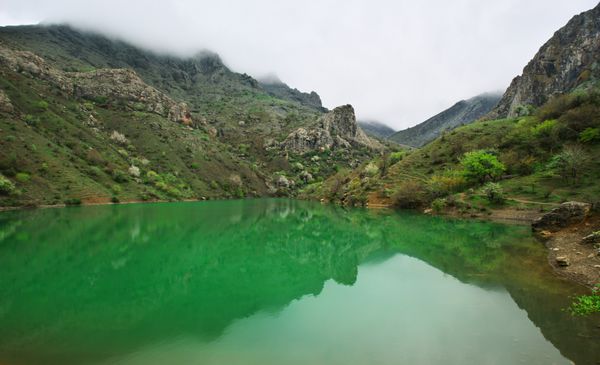 دریاچه کوهستانی آرام با آب سبز و انعکاس در هوای ابری همراه با مه آرپات کریمه