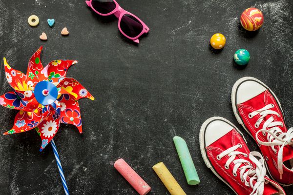 اسباب بازی ها و کفش های کتانی قرمز روی تخته سیاه سیاه از بالا دوران کودکی - مفهوم سرگرمی تعطیلات یا تابستان طرح پس زمینه با متن رایگان sp