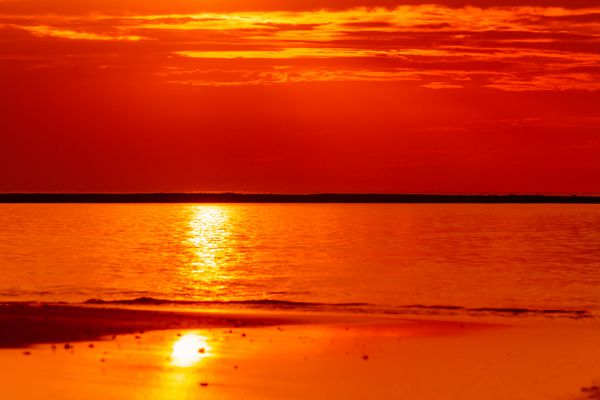 آسمان نارنجی آتشین غروب خورشید بر فراز دریا