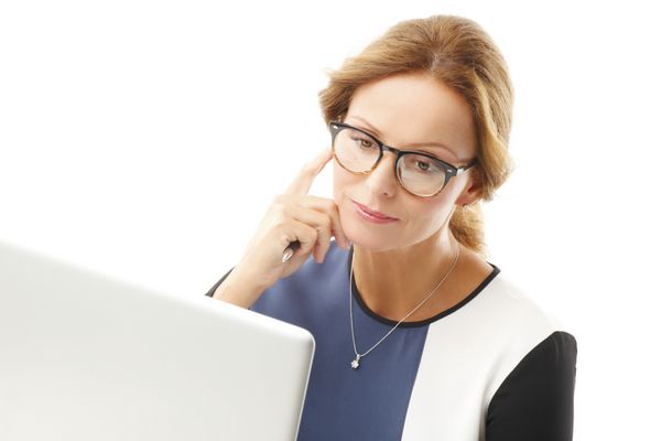پرتره زن تاجر بالغ که با لپ تاپ کار می کند در حالی که در مقابل پس زمینه سفید نشسته است