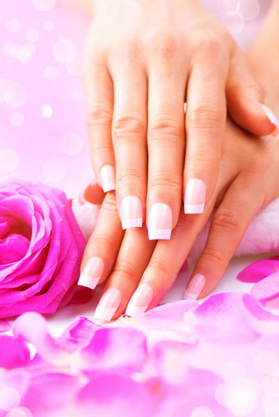 مانیکور آبگرم دست دست های زیبای زن پوست نرم ناخن های زیبا با گلبرگ های گل رز صورتی دست های زن سالم سالن زیبایی رفتار ناخن های زیبای زنانه با مانیکور فرانسوی