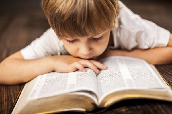 پسر کوچکی که در حال مطالعه متون مقدس است