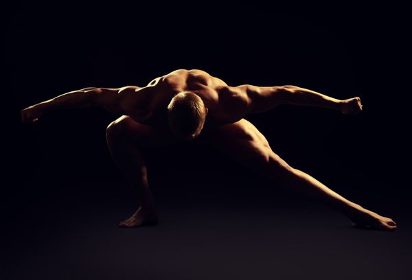 مرد عضلانی ورزشکار که روی پس زمینه سیاه ژست گرفته است زیبایی مردانه پرورش اندام ورزش ها