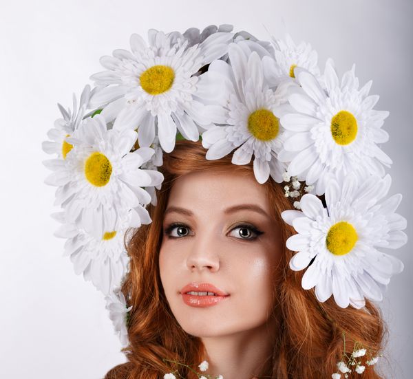 دختر زیبای مو قرمز با تاج گل بابونه روی سرش گل های مروارید بزرگ روی موهای مجعد بلند