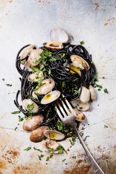 ماکارونی غذاهای دریایی با فونگوله اسپاگتی صدفی در زمینه بافت فولادی