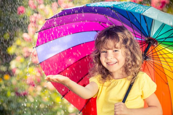 کودک شاد زیر باران بچه خنده دار در فضای باز در پارک بهار