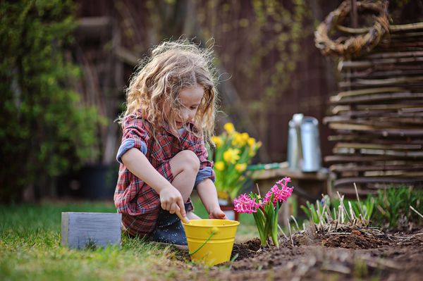 دختر بچه ناز در باغ بهاری باغبان کوچک بازی می کند و گل سنبل را روی زمین می کارد فعالیت های فصلی در فضای باز کودکی شاد