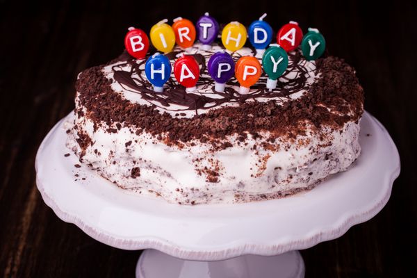 یک کیک و شمع هایی که نوشته تولدت مبارک