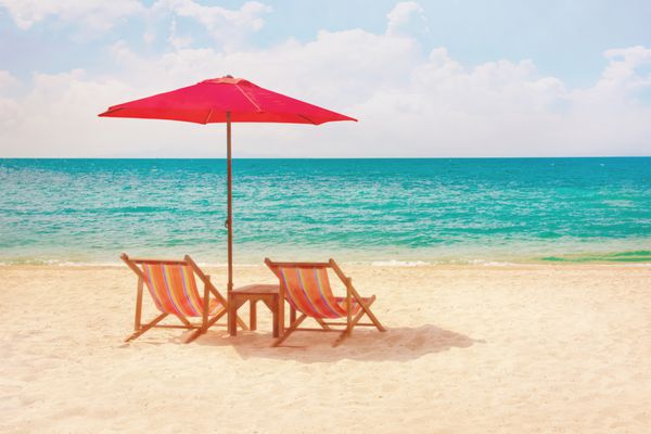 دو صندلی استراحت و یک چتر آفتابگیر در ساحل