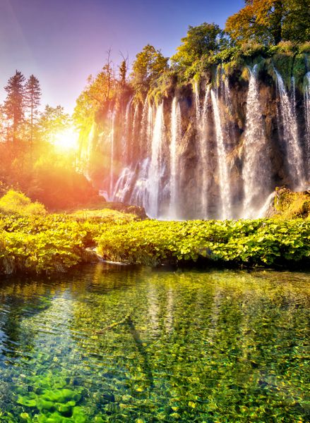منظره باشکوه بر روی آبشار با آب فیروزه ای و پرتوهای آفتابی در پارک ملی دریاچه های پلیتویس جنگلی که از نور خورشید می درخشد کرواسی اروپا صحنه دراماتیک صبح دنیای زیبایی افکت اینستاگرام