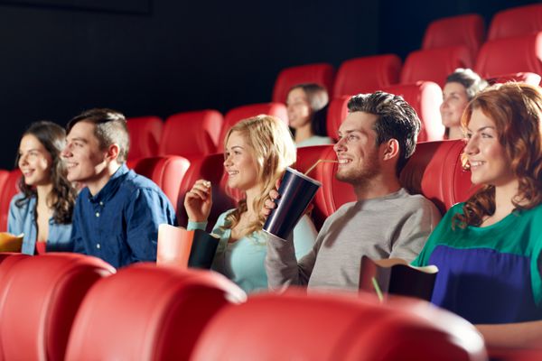 سینما سرگرمی و مفهوم مردم - دوستان خوشحال در حال تماشای فیلم در تئاتر