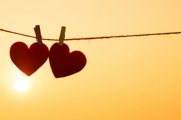 عشق برای روز - دو قلب قرمز به همراه شبح غروب آفتاب به طناب آویزان شده است