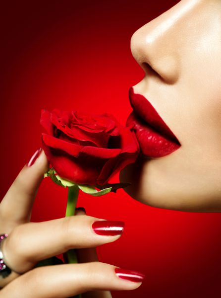 زن مدل زیبا در حال بوسیدن گل رز قرمز لب قرمز ناخن و گل رز دختر زیبایی آرایش و مانیکور دهان حسی لب های قرمز رنگ خیابان طراحی روز بخشی از f