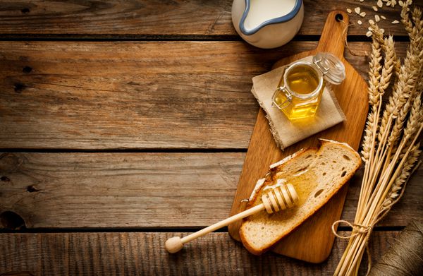 عسل در یک شیشه تکه نان گندم و شیر روی یک میز چوبی قدیمی و قدیمی از بالا مفهوم صبحانه به سبک روستایی یا روستایی طرح پس زمینه با متن رایگان sp