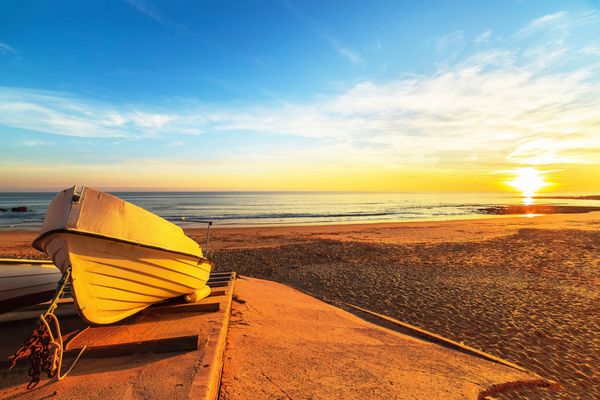 قایق در نور گرم غروب خورشید در ساحل ماهیگیران praia dos pescadores در آلبوفیرا پرتغال