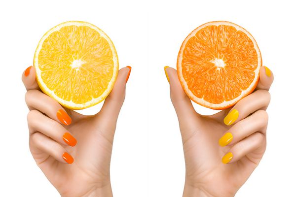 دست های زن شیک با ناخن های نارنجی و زرد که تکه هایی از مرکبات را در دست دارند نزدیک جدا شده در پس زمینه سفید مفهوم رژیم غذایی سالم سالم