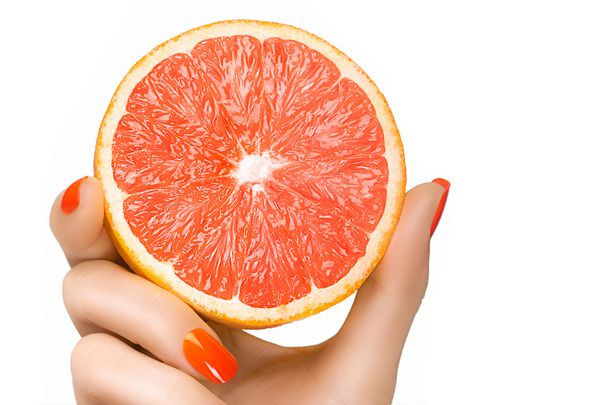 دست زن با ناخن های بسیار آراسته با لاک ناخن نارنجی که یک گریپ فروت دلپذیر را در تناسب رنگ در یک مفهوم رژیم غذایی سالم نگه داشته است روی سفید جدا شده با کپی sp برای متن