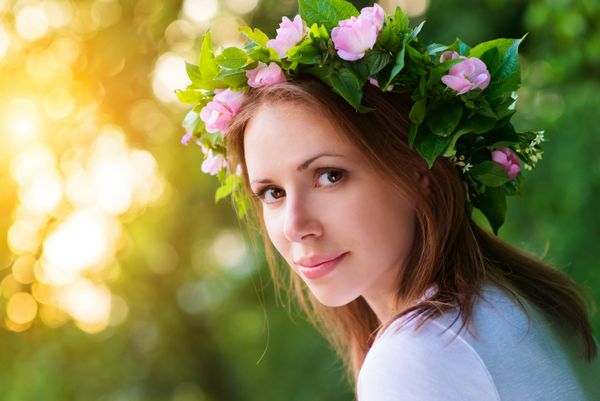 زن جوان جذاب با تاج گل روی سرش با غروب خورشید در پس زمینه