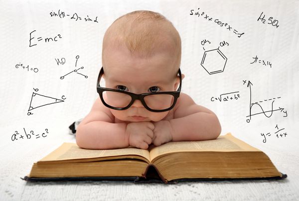 پرتره خنده دار کودک ناز با عینک که روی کتاب قدیمی دراز کشیده و به تمام دانش جهان فکر می کند