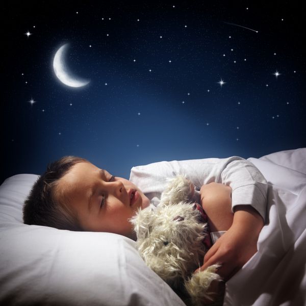 کودکی که در رختخوابش زیر ماه ستاره ها و آسمان آبی شب می خوابد و رویا می بیند