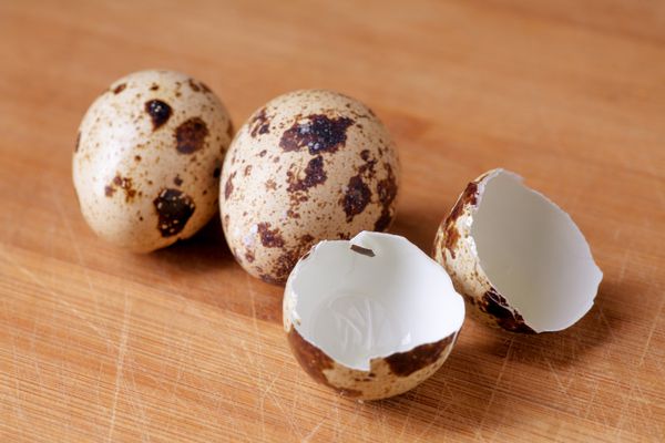 تخم بلدرچین و پوسته تخم مرغ در زمینه چوبی مفهوم غذای سالم