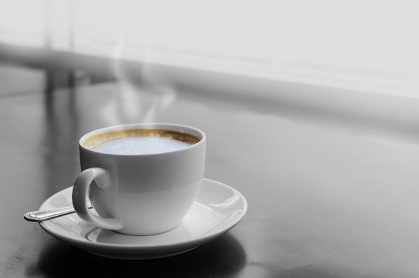 نمای بالای یک فنجان قهوه کاپوچینو روی میز چوبی