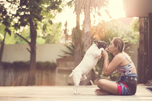 زنانی که سگی را در آغوش می گیرند و می بوسند آنها بازیگوش و شاد هستند