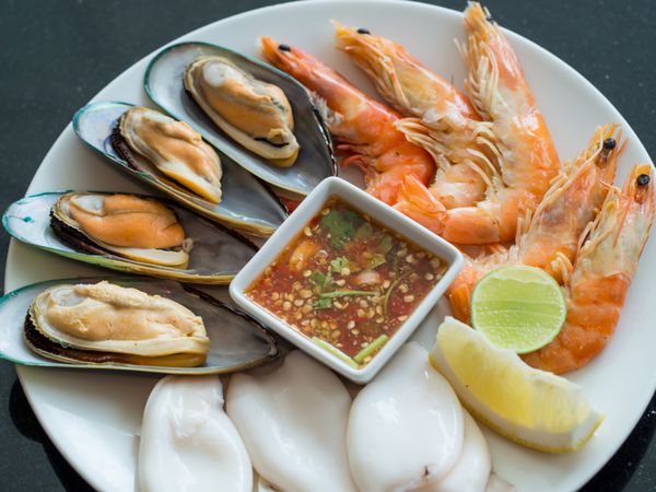 بشقاب غذاهای دریایی شامل میگو ماهی مرکب صدف و سس غذاهای دریایی تایلندی