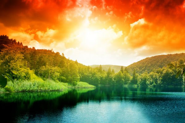 دریاچه آبی سبز در جنگل و غروب خورشید
